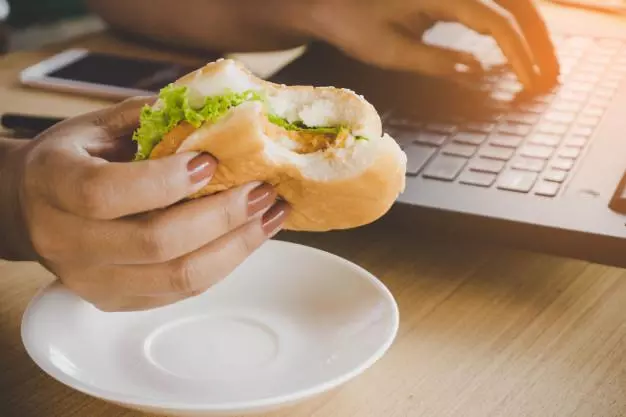 mujer-trabajadora-ocupada-comiendo-hamburguesa-comida-chatarra-mientras-trabajaba-computadora-portatil-oficina_34670-81 3 mauvaises habitudes à perdre quand vous écrivez